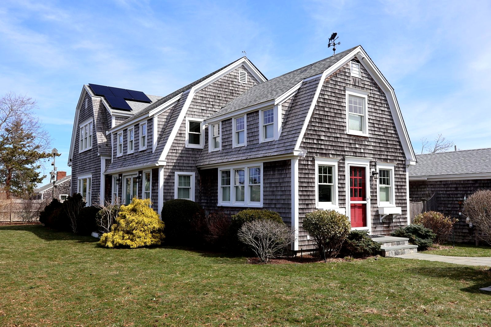 Cape Cod gambrel shingle home with red door and weather vane